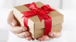 Hands holding a gift box wrapped with a red ribbon